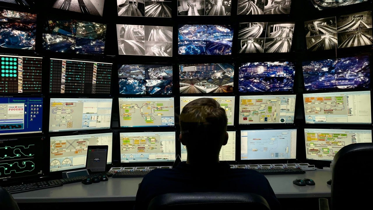 Control room operator monitoring multiple screens displaying satellite imagery, maps, and data feeds
