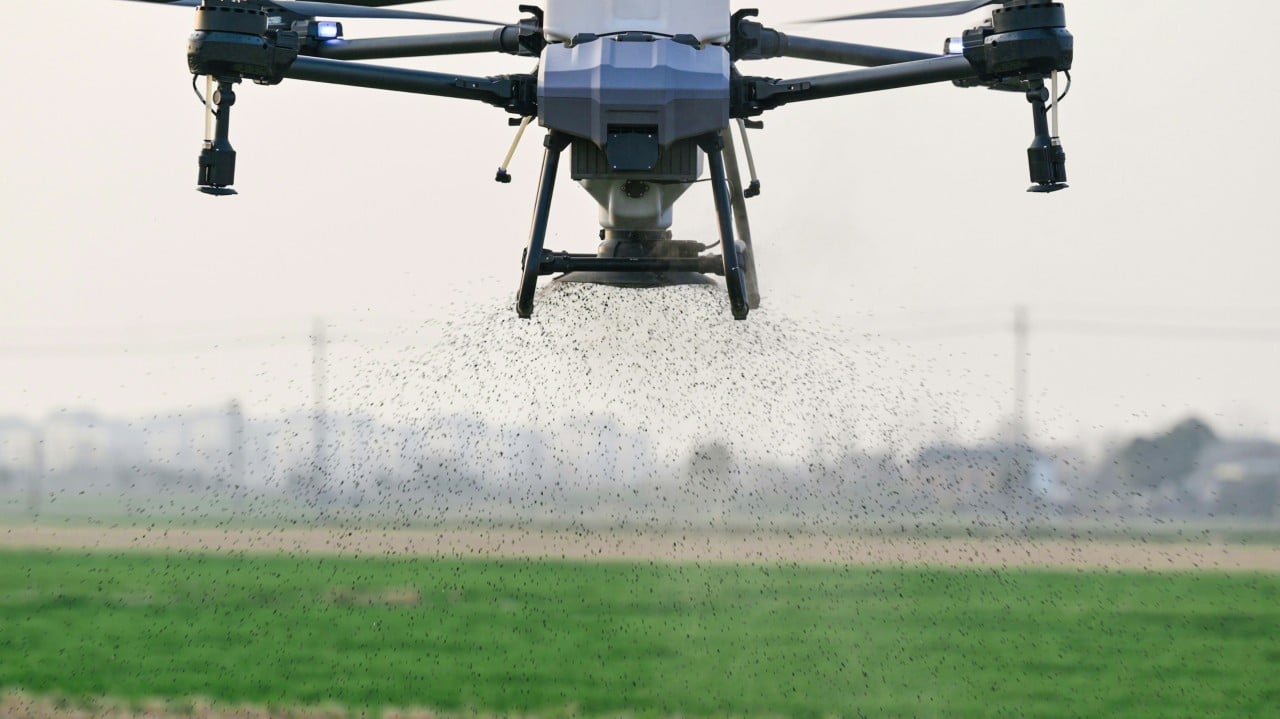 Agricultural drone spraying crops over a green field with extended spray boom arms